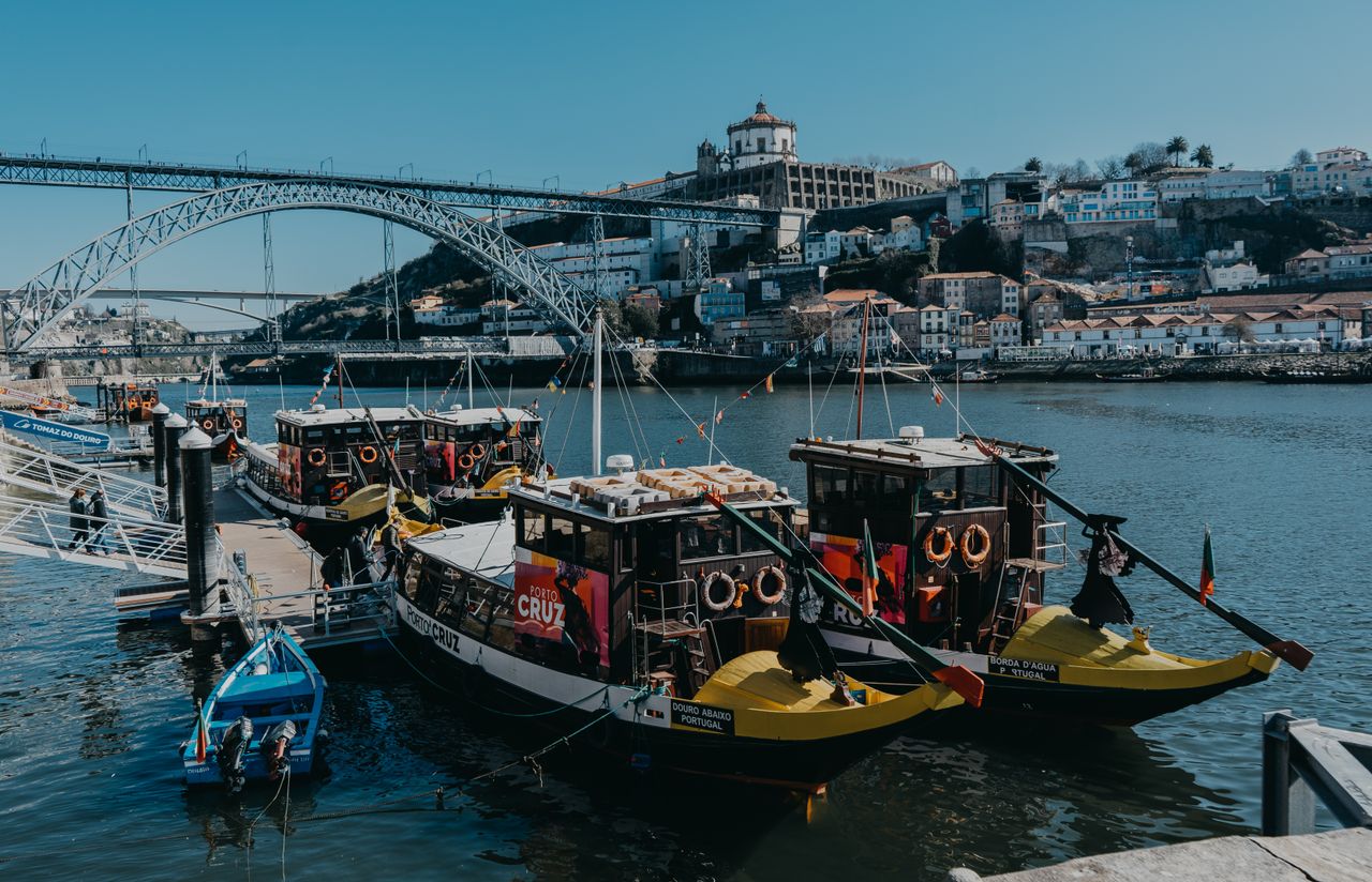 Scenic view of boats on the Douro River with the iconic Dom Luis I Bridge in Porto, Portugal.