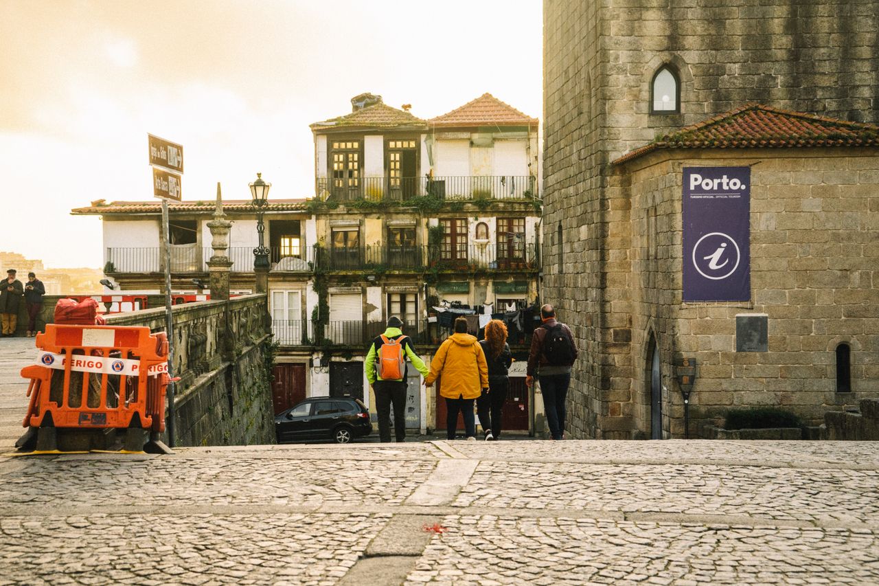 Group of people walking down cobblestone streets in Porto, Portugal, showcasing historic architecture.