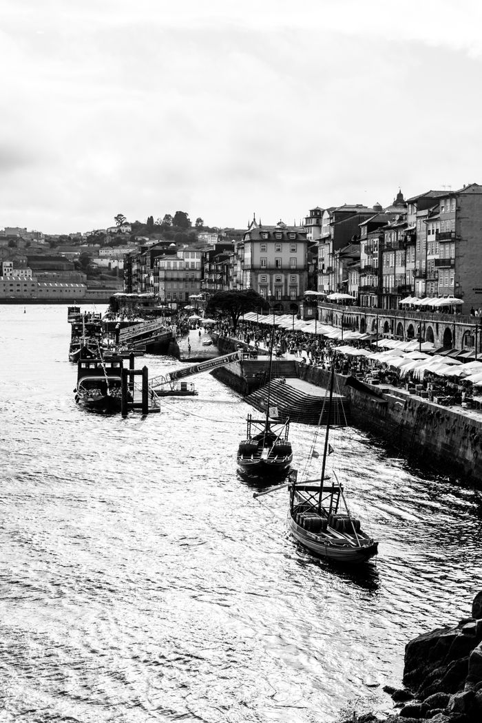 A black and white street photography view of boats along the Porto riverfront.